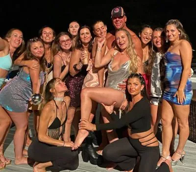 Male stripper taking a group photo with a bachelorette party of 13 ladies