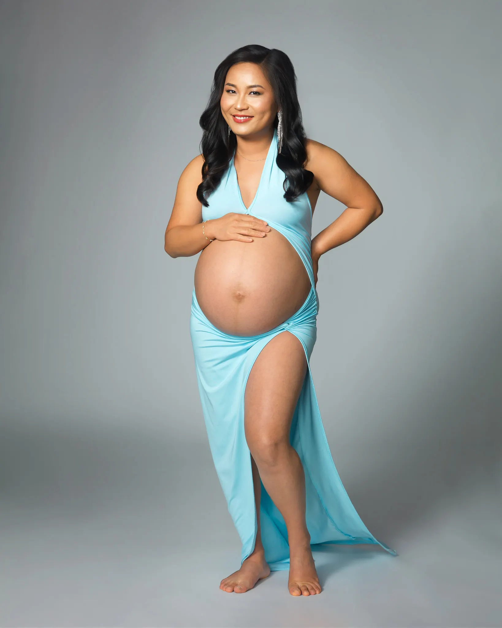 Darkly lit maternity portrait of woman in a pink gown