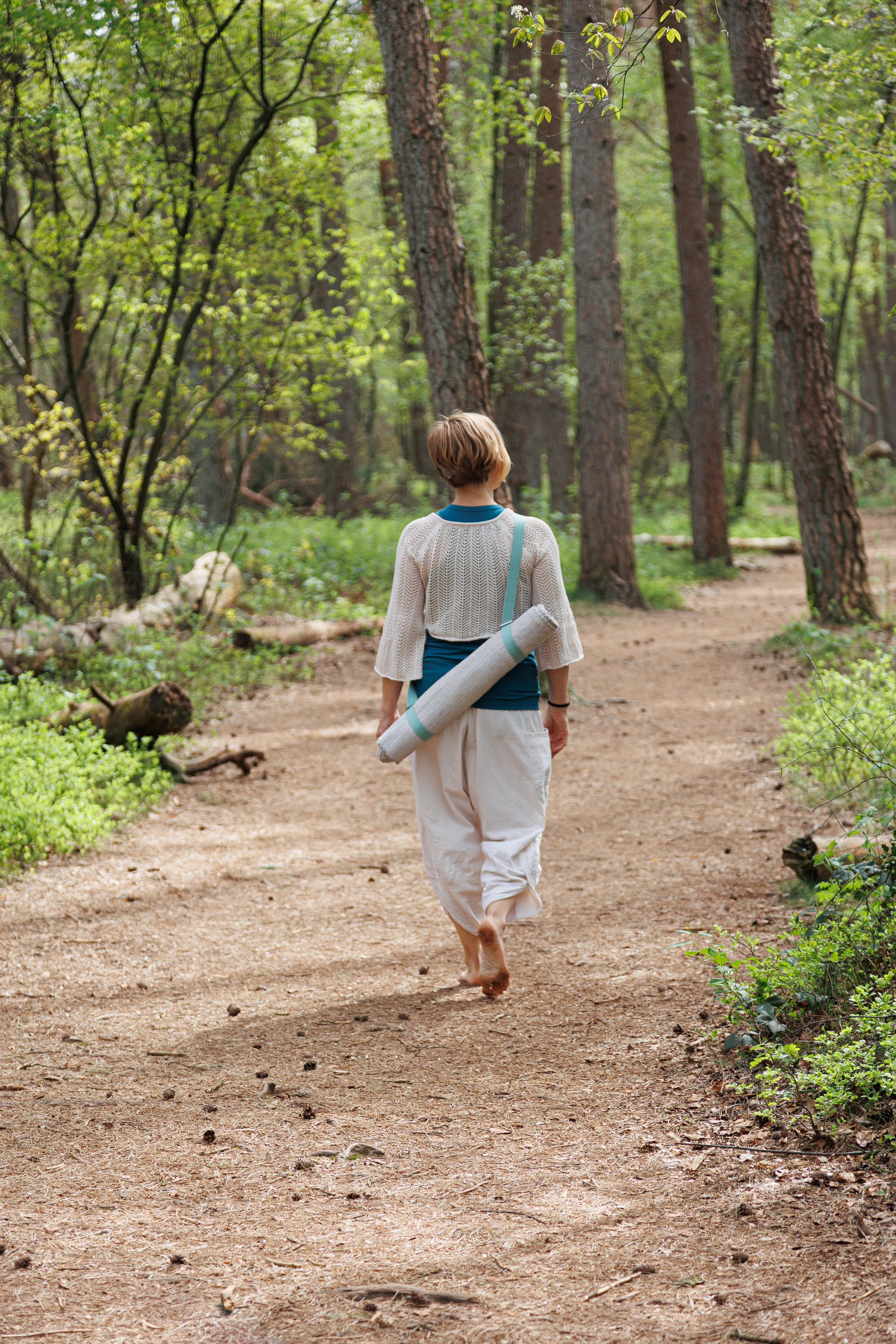 ingrid loopt met een yogamat op haar rug in het bos