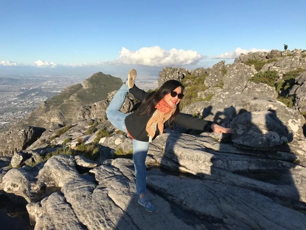 Dr. Ma Cherie Cortez strikes a fun yoga pose on top of Table Mountain in South Africa. Explore her vibrant personality and expertise as a world-renowned Expat Leader and Agile Coach, blending wellness with professional excellence.