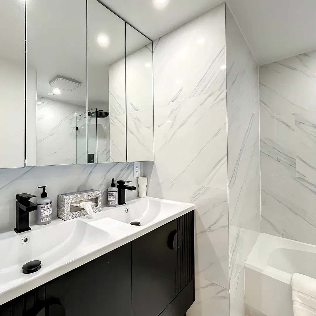 Bathroom Nr 1 with dimmer lights, a dual sink vanity, shower & bathtub combo, and double mirror wall cabinets.