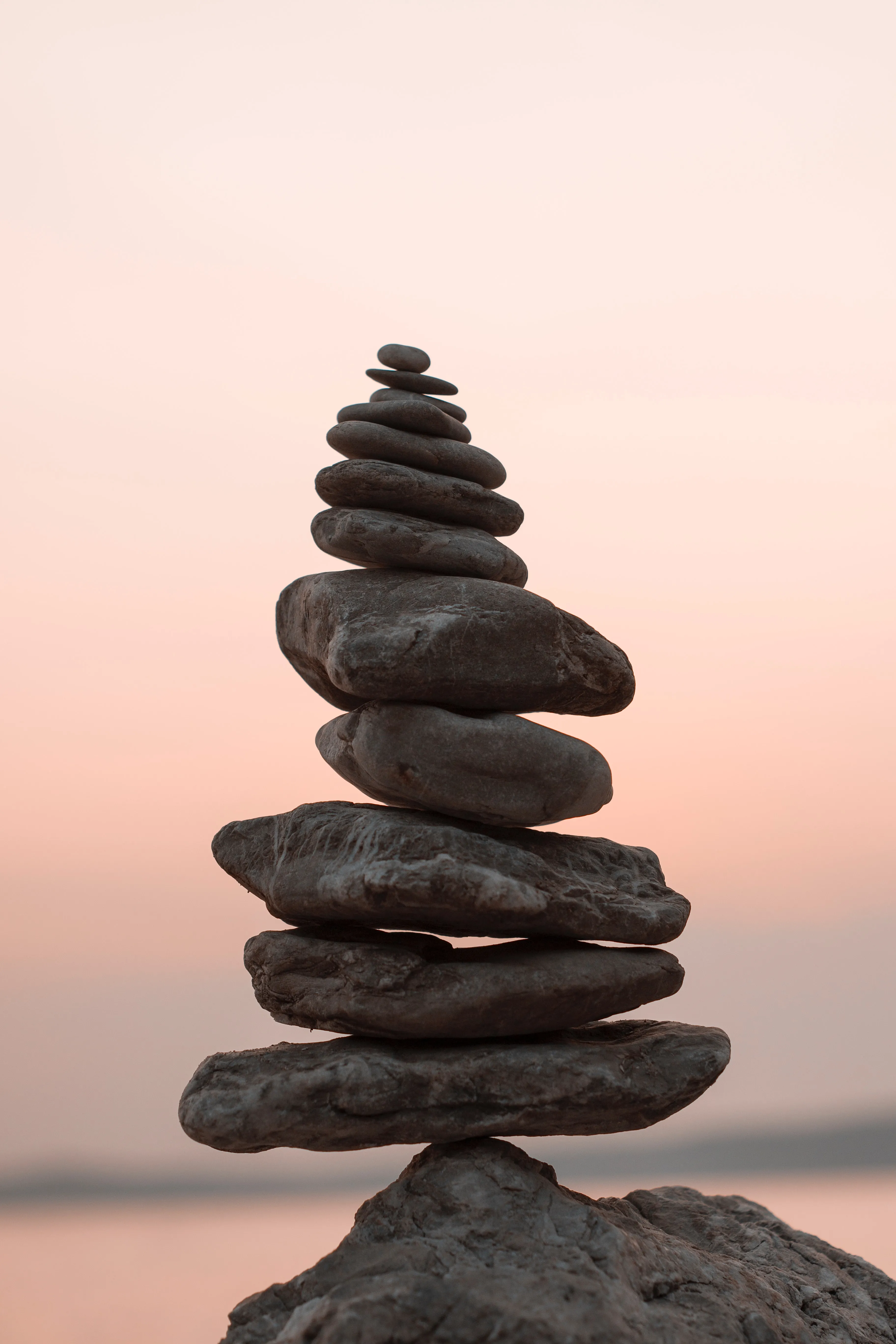 column of rocks perched on a boulder overlooking a sunset looking out to sea