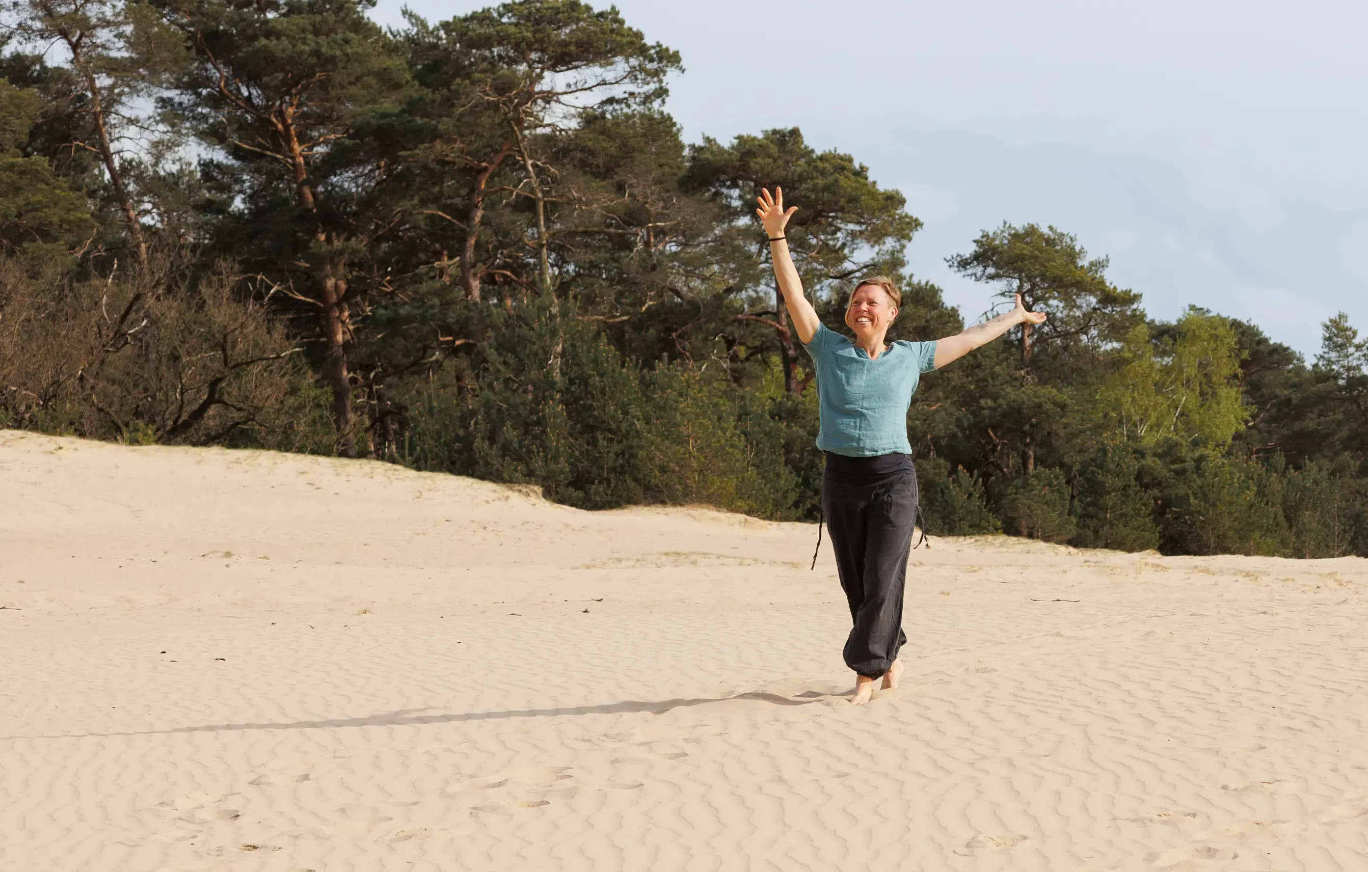 Ingrid staat met handen omhoog op heuvel