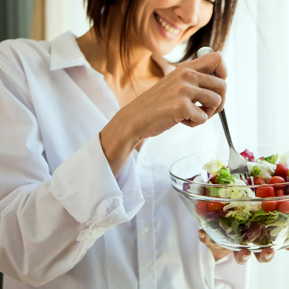 Cleanse image woman eating a large healthy salad