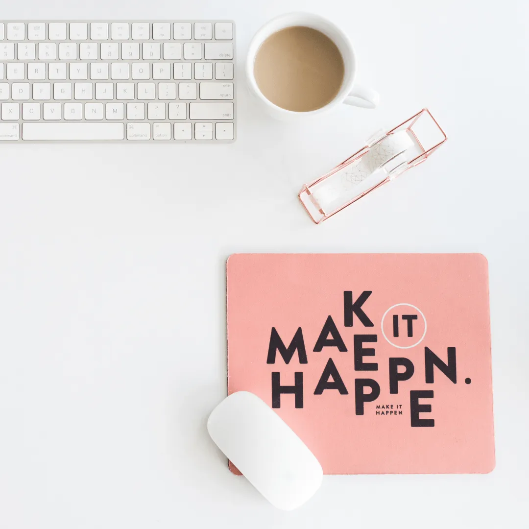 An image of a table with a keyboard, cup of coffee, and a sign of Make it Happen 