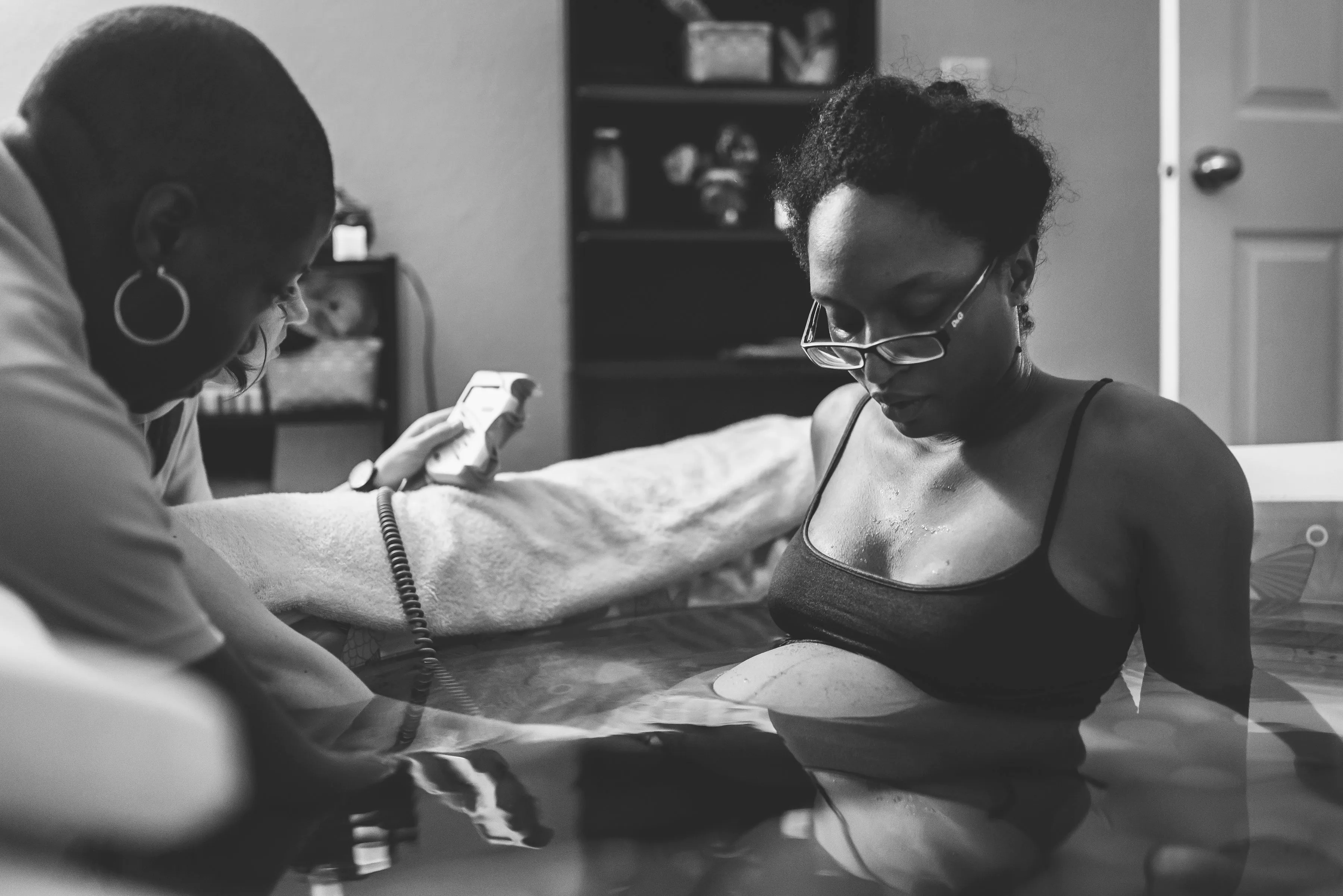 Crystal in birthing pool during home birth, midwife using doppler to check baby's heartbeat.