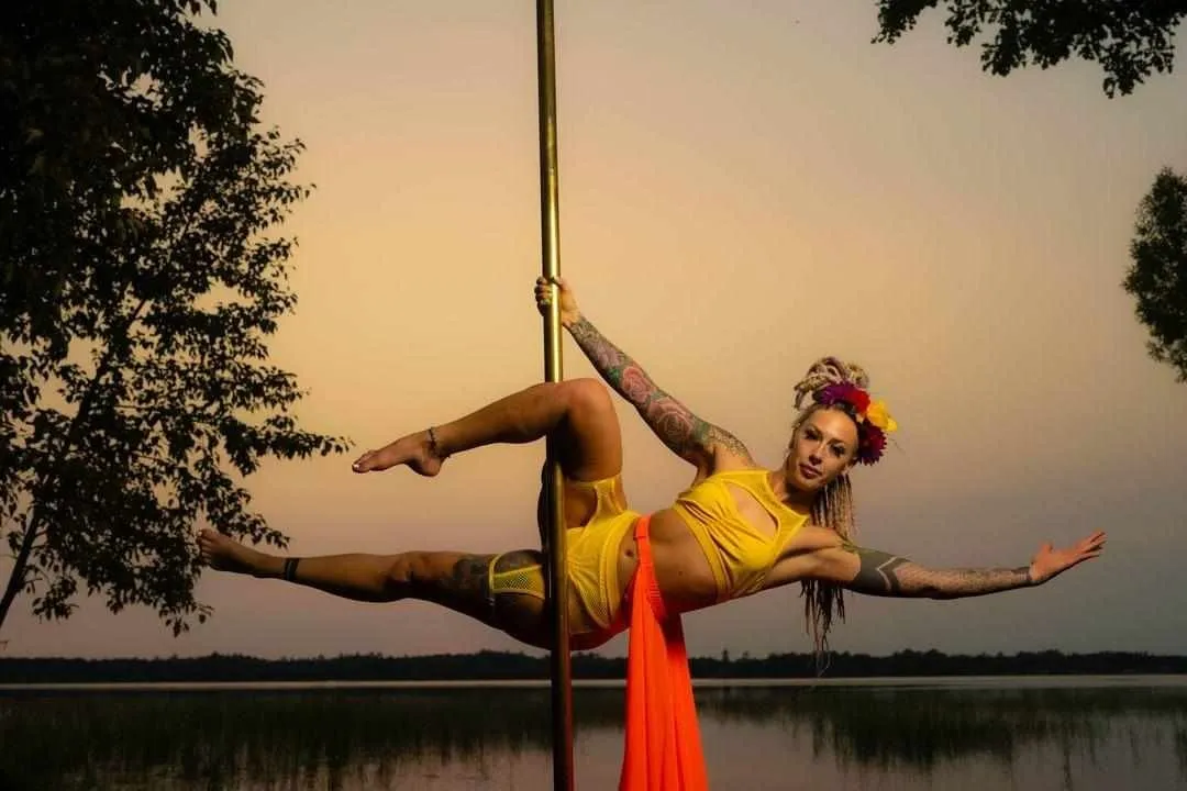 Amanda in Viva pose, facing the camera straight on, her orange skirt hanging down in front of the sunset over the lake. 