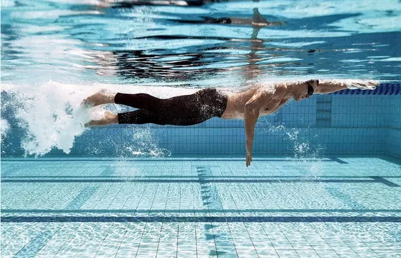 A man swimming underwater doing the freestyle stroke.