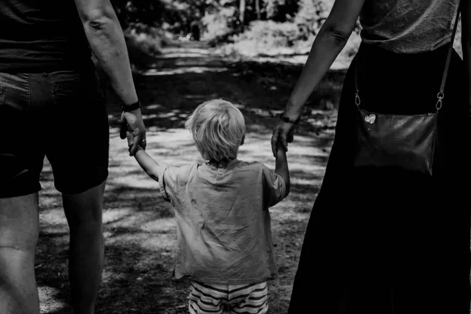 parents holding their child hands in the park