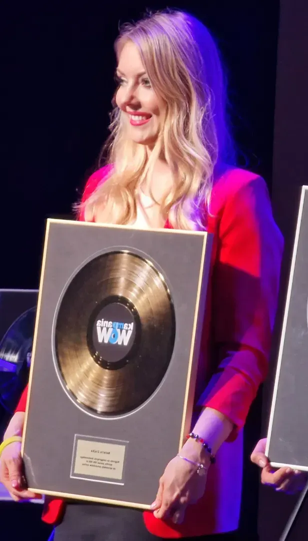 A blonde wman holding an award