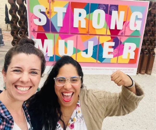 Ally and Gabby in front of a sign that says Strong Mujer
