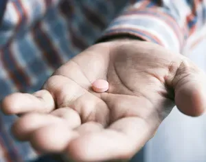 A hand holding a pill