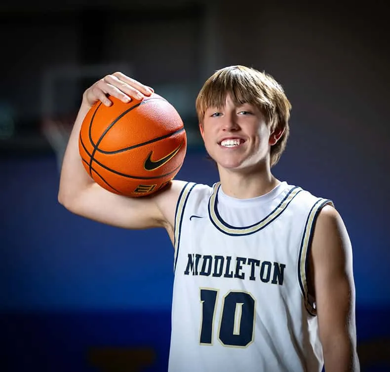 boy basketball player close up with ball on shoulder smiling