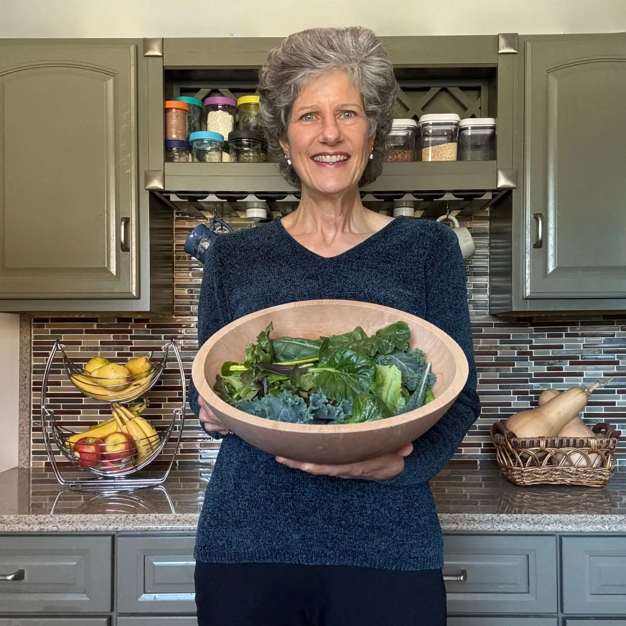 Woman holding fresh greens harvested from a Tower Garden in a home kitchen