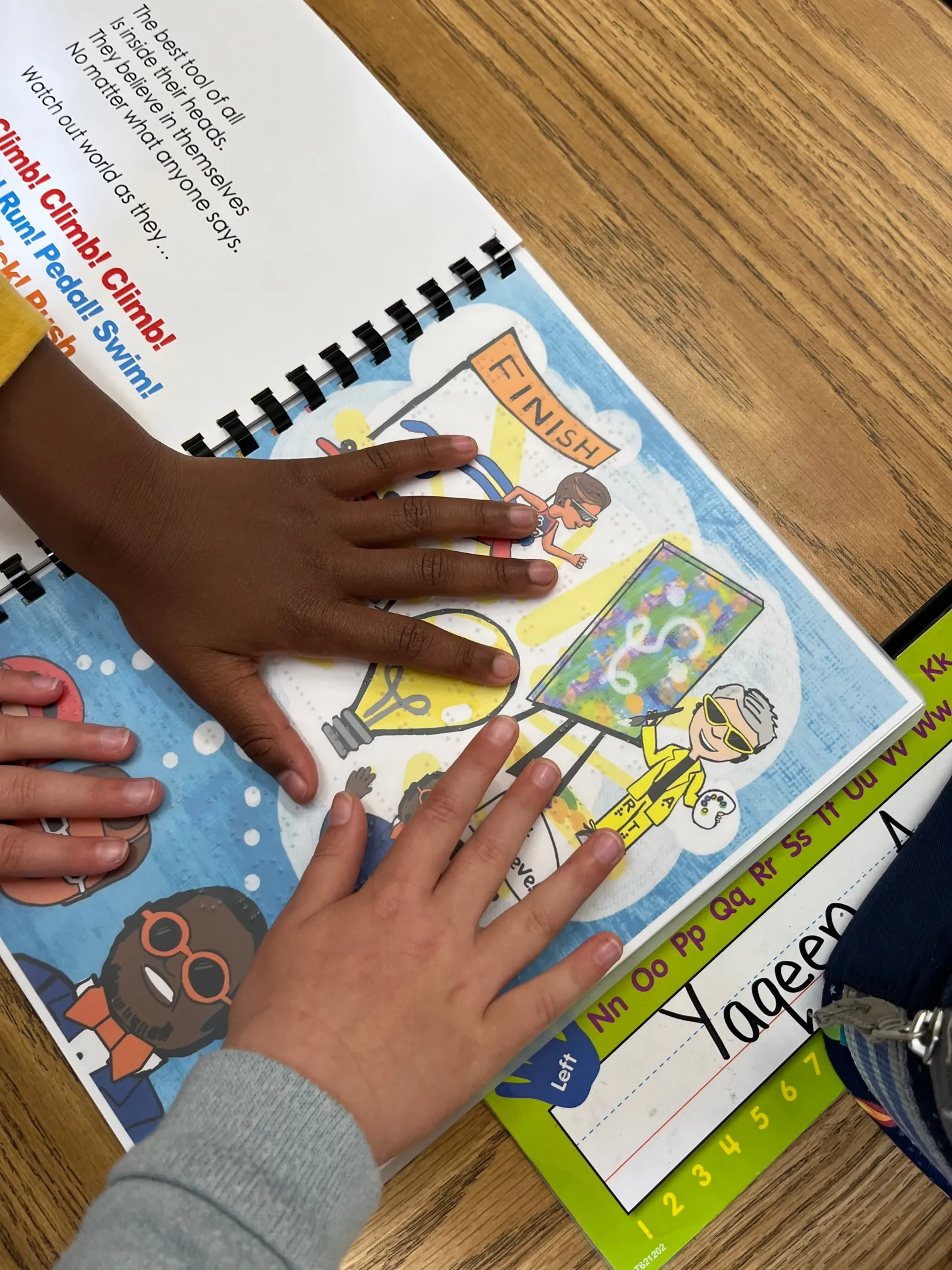 young children's hands on the braille in the book