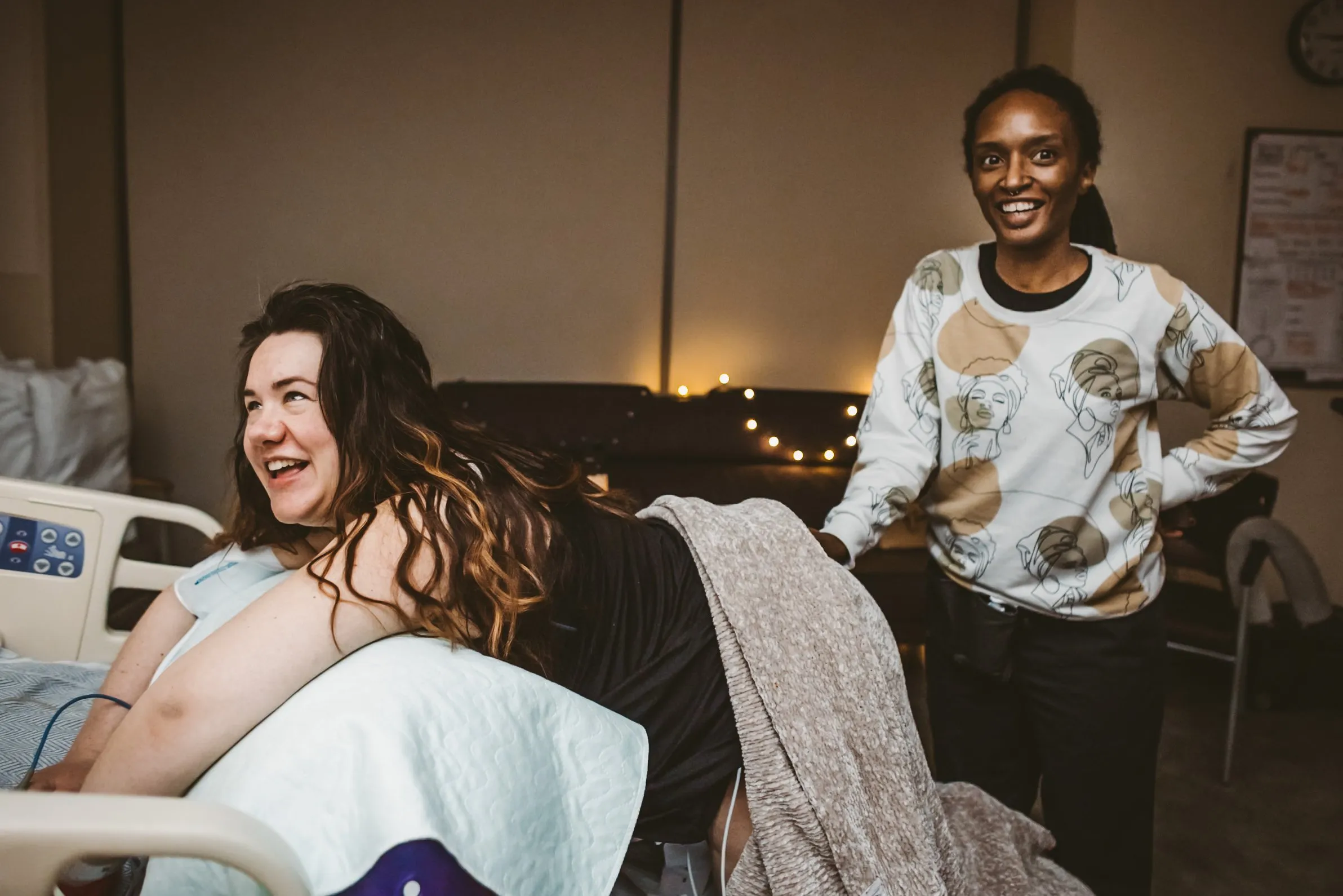 Client smiling while doula offers sacral support during labor