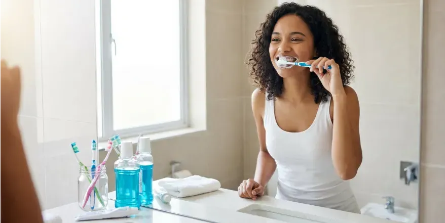 Young woman brushing her teeth in a well lit bathroom