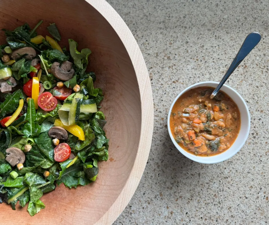 Zucchini ribbon garden salad with sautéed mushrooms served alongside white bean and kale soup in a bowl