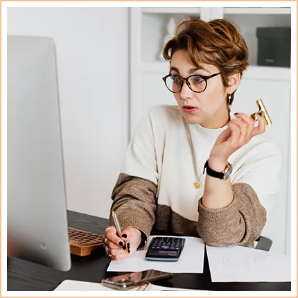 woman looking at computer and writing on notepad