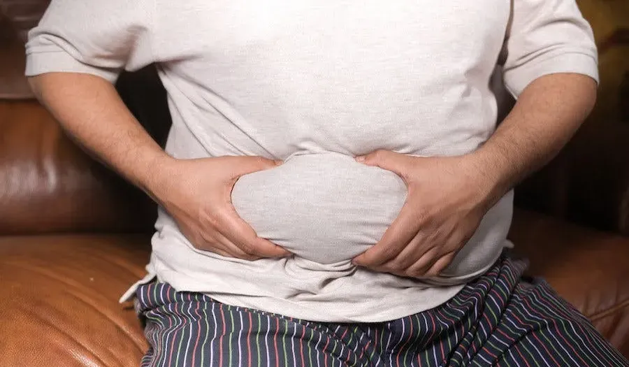 A man grabbing a big fat roll on his belly