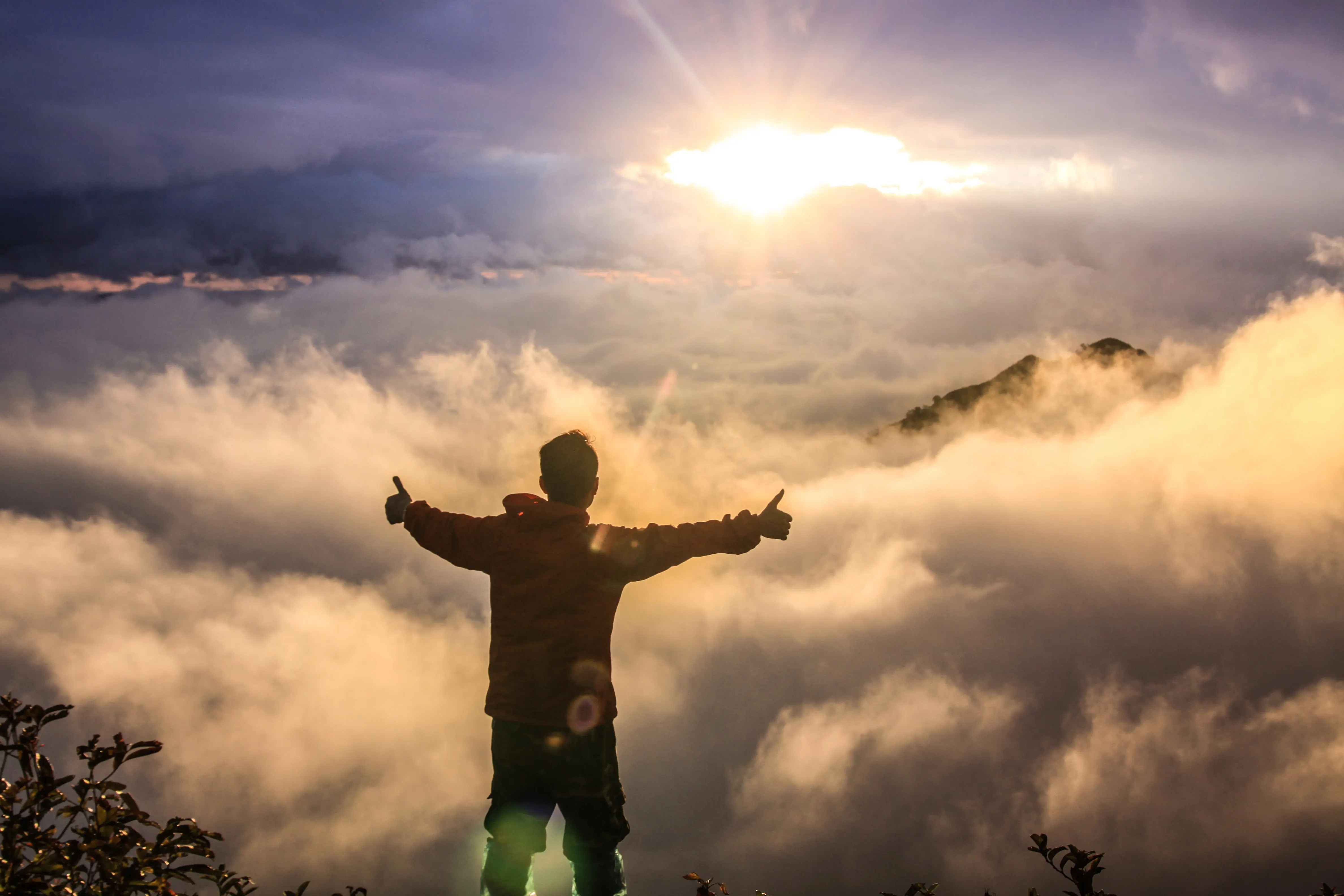 Leader standing above clouds at sunrise — clarity and calm leadership