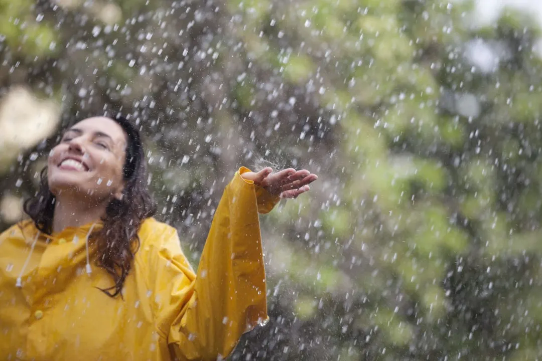 Lady in gold long sleeved blouse looking up to sky left hand palm facing up , with huge smi
