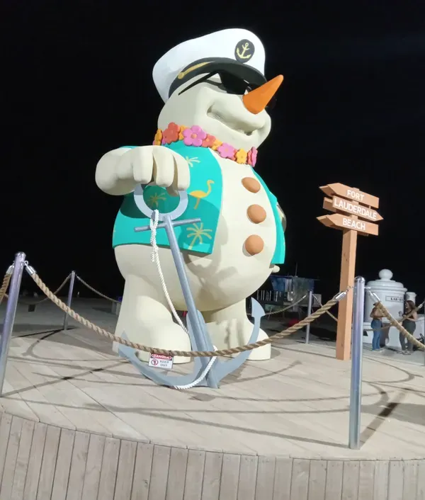 A statue of a snowman wearing a jacket and sunshades, holding an anchor