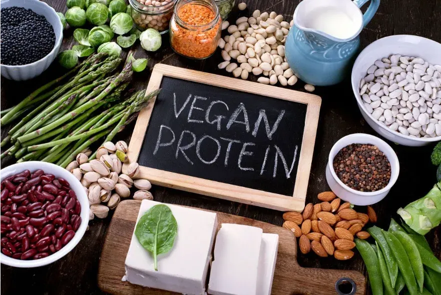A table full of vegan proteins with a small chalkboard with the words "vegan protein".