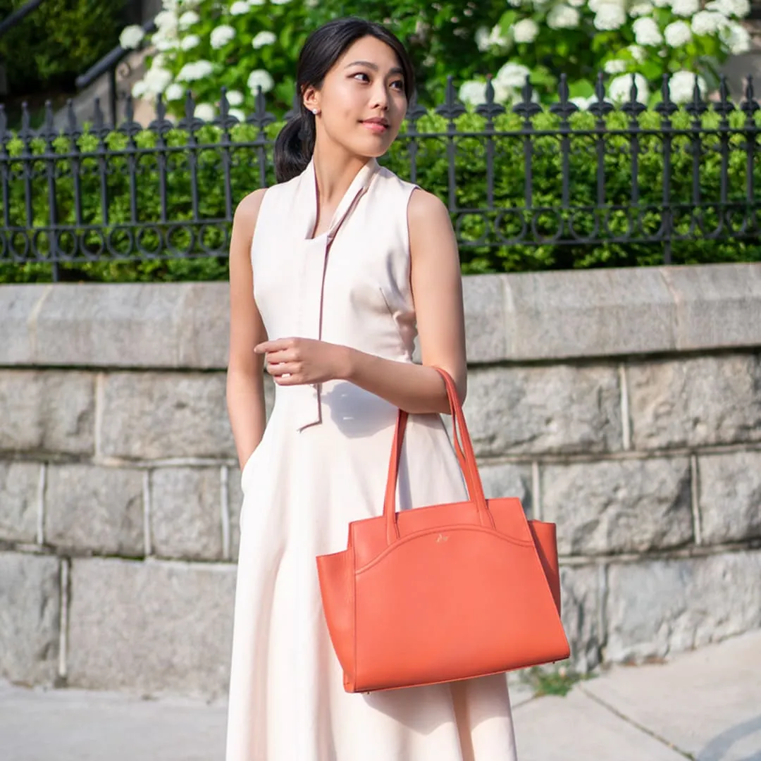 An elegant lady is wearing a canyon orange Tang Dynasty Grace Tote, a bag that is inspired by Tang Dynasty, designed by Shen Yun Collections, made in Spain. 