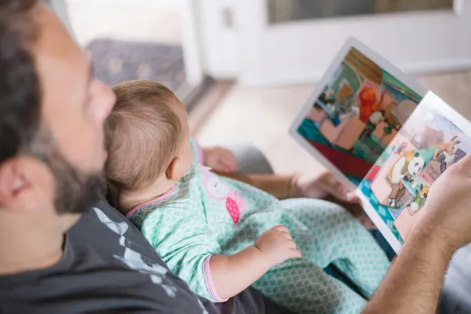 dad reading a book to his new born baby