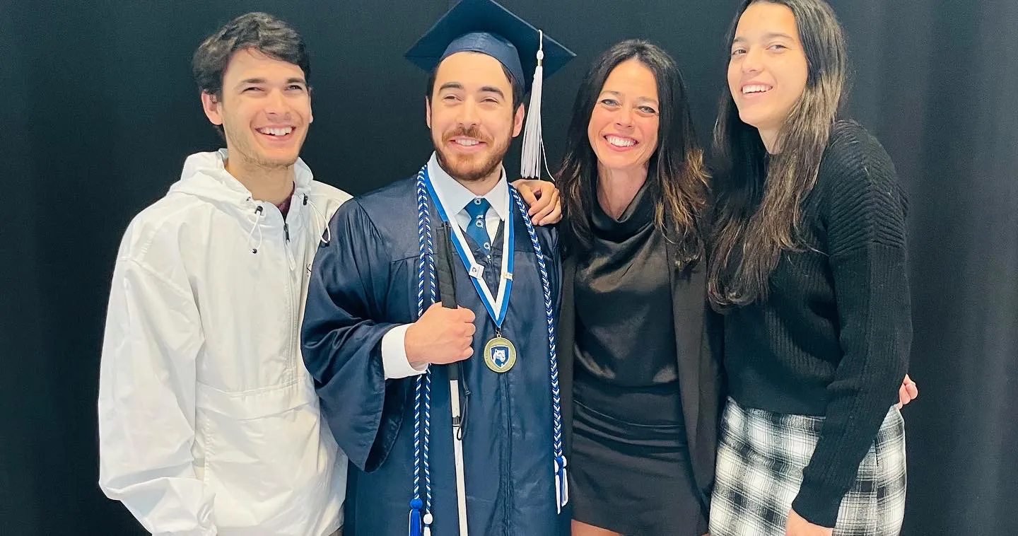 Smedley family with Michael dressed in blue graduation cap and gown holding his white cane