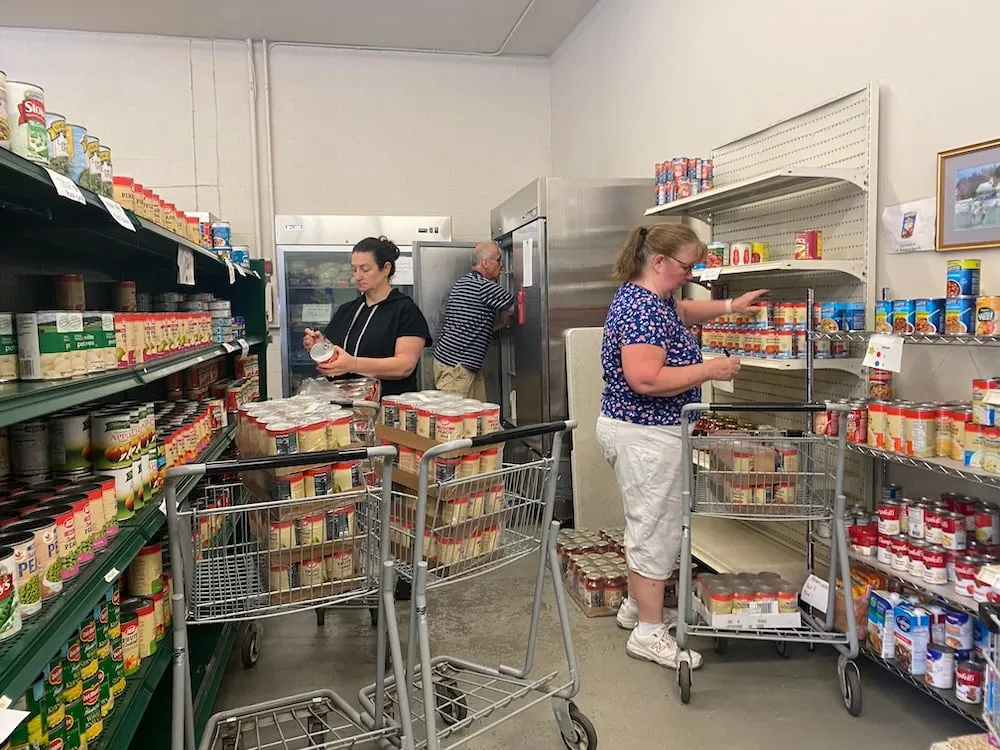 Three volunteers of Madison Community Services as they stock the Pauline Baldwin Food Pantry