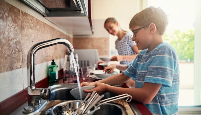 Boy helping mom do the dishes.