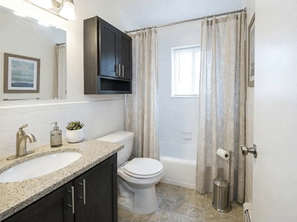 <alt=“Modern furnished bathroom at AHA Global Holdings corporate housing in Ann Arbor, featuring updated cabinets, granite counters, and clean neutral decor.”>
