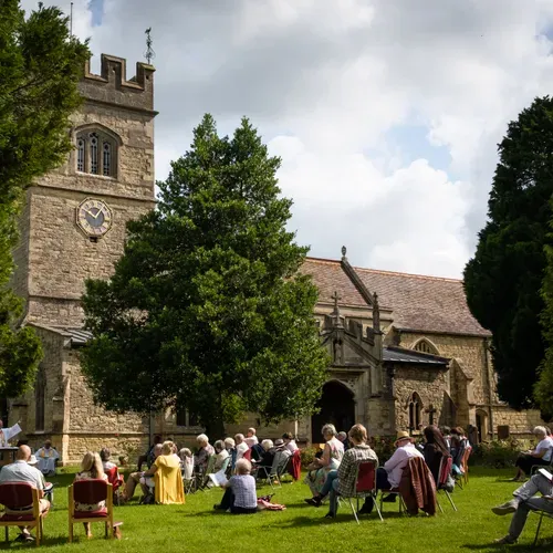 People sit on picnic chairs in the St Laurence churchyard