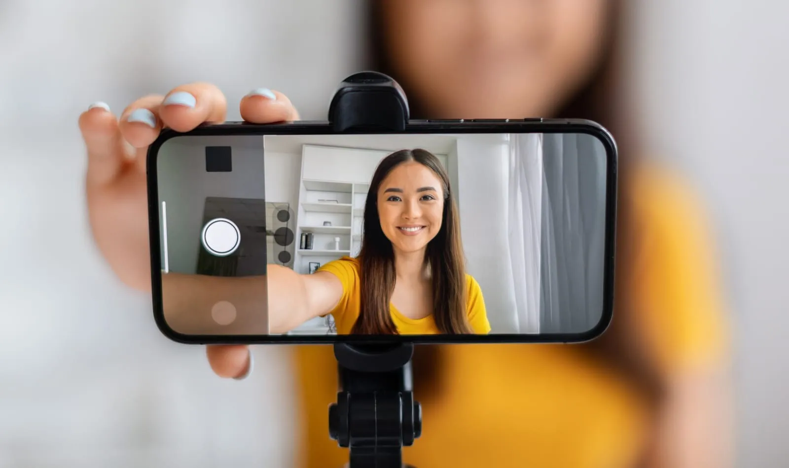 mujer-con-un-top-amarillo-grabando-un-vídeo-con-un-teléfono-inteligente-montado-en-un-tripode