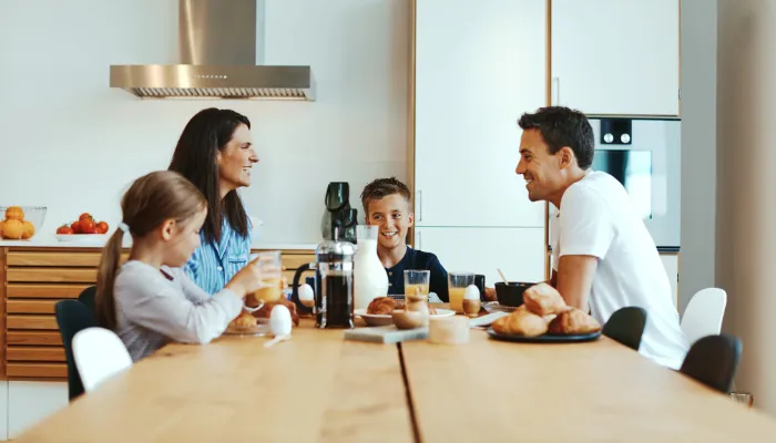 Family eating breakfast in the kitchen together.