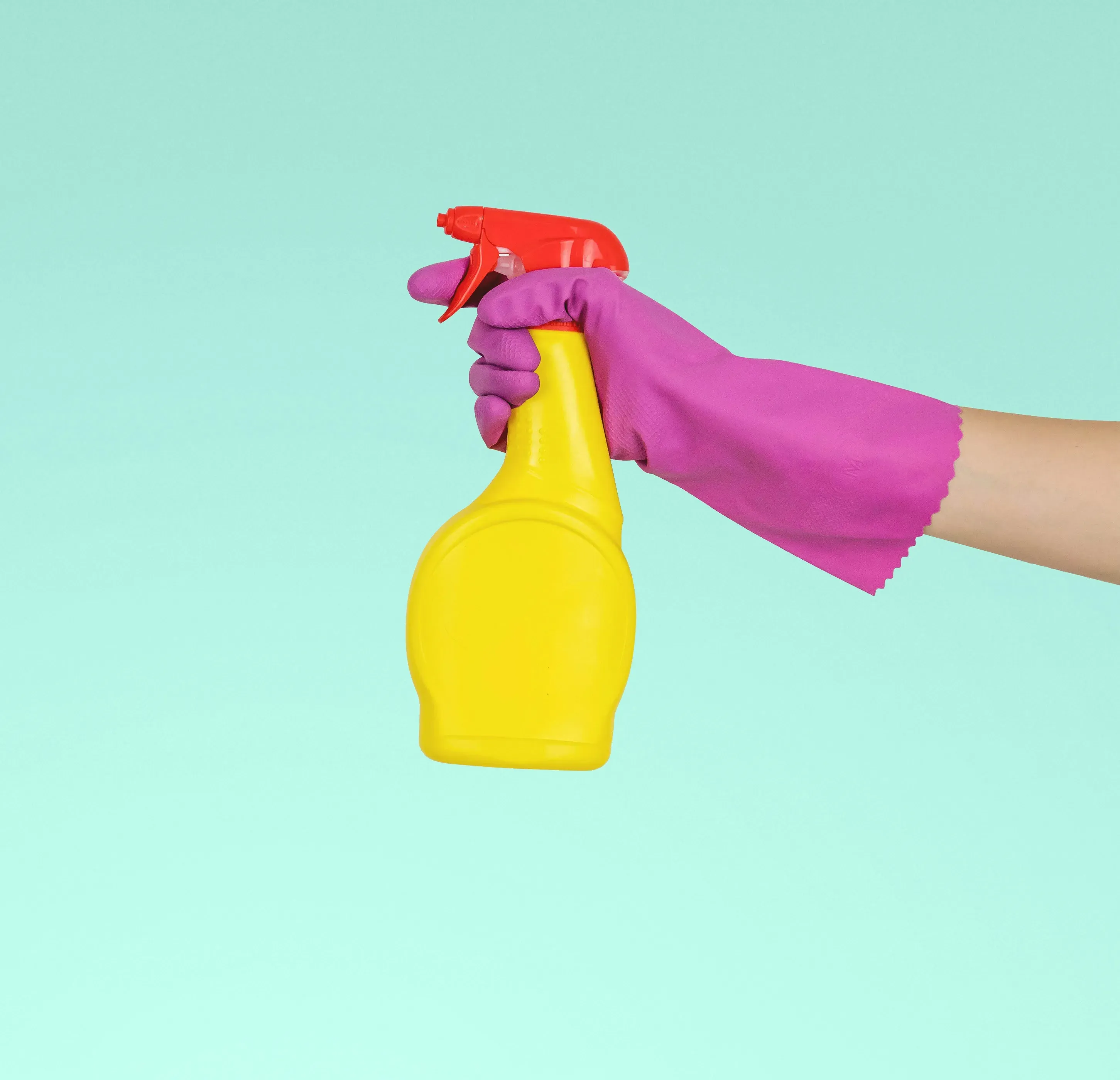 Hand with rubber glove spraying a cleaning product