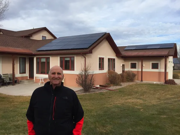 Man standing in front of home with solar panels installed on the roof
