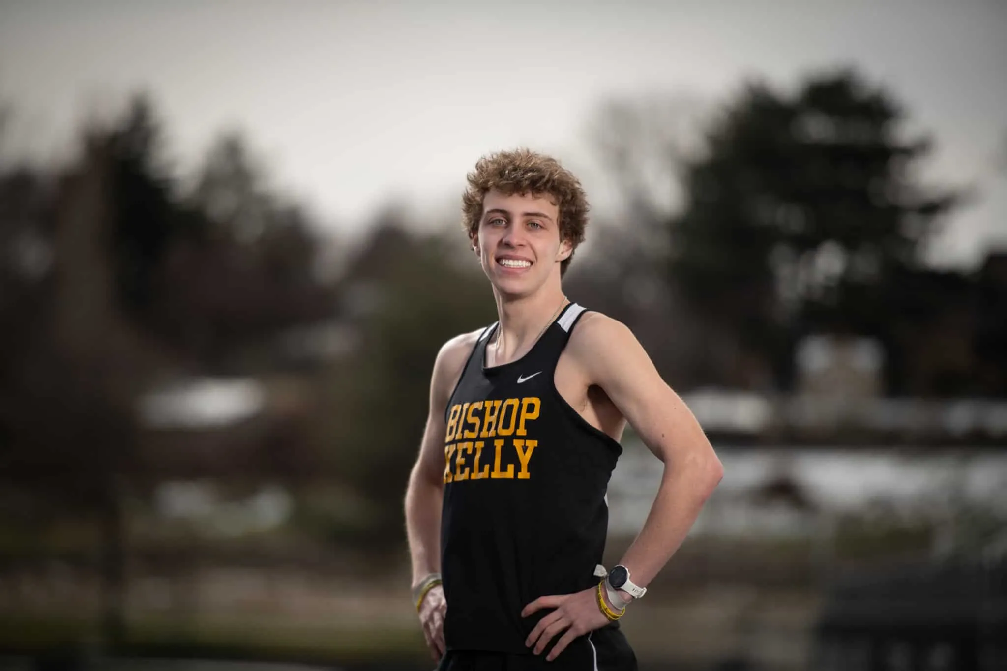 High school track athlete standing on Bishop Kelly's track after a win