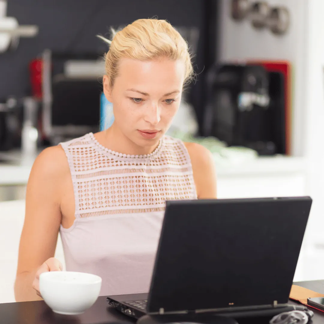 Woman working on laptop with coffee
