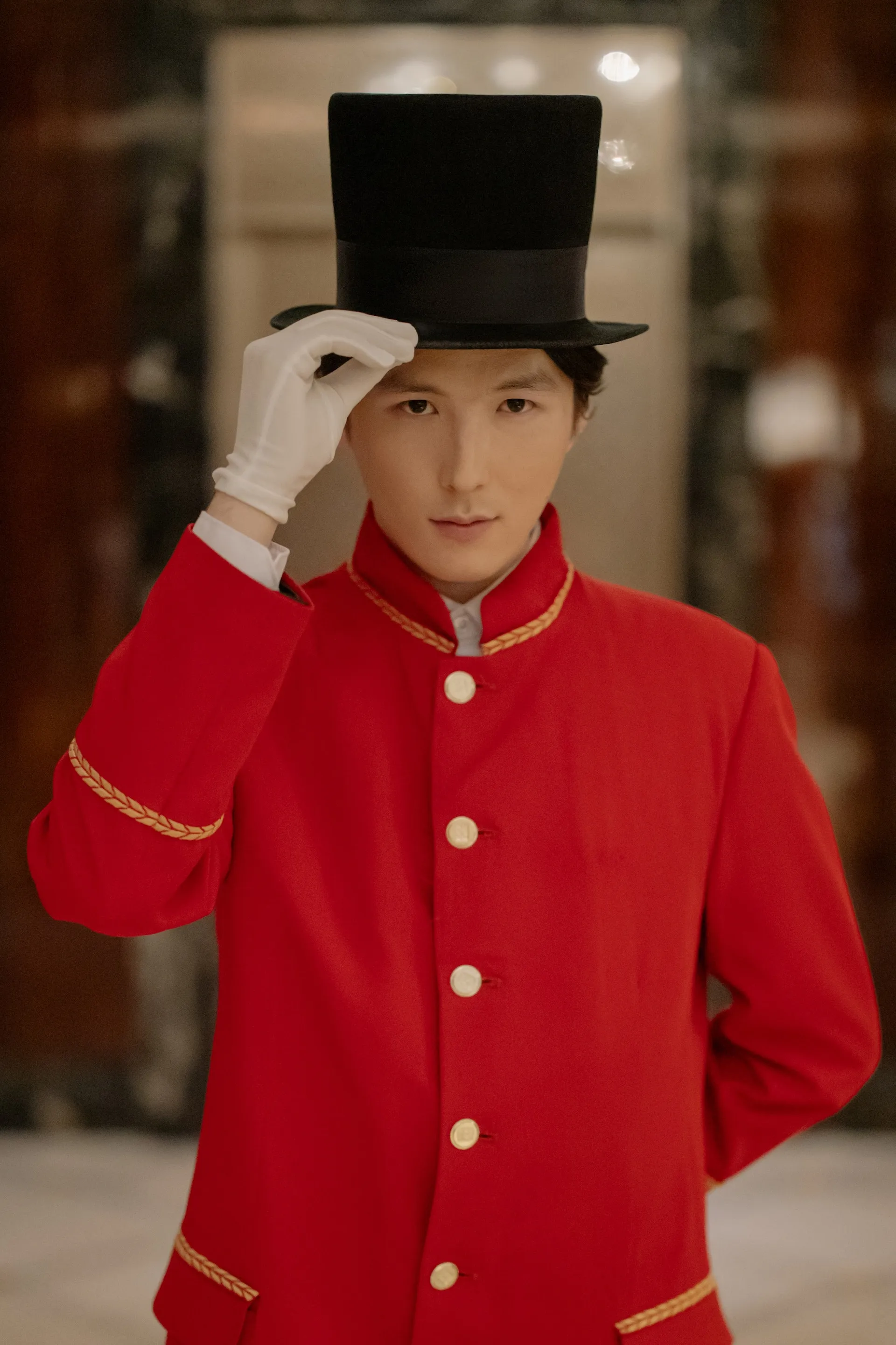 Concierge wearing a black top hat and red coat