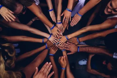 Single hands piled on top of eachother while standing in a circle to show different skin colours 