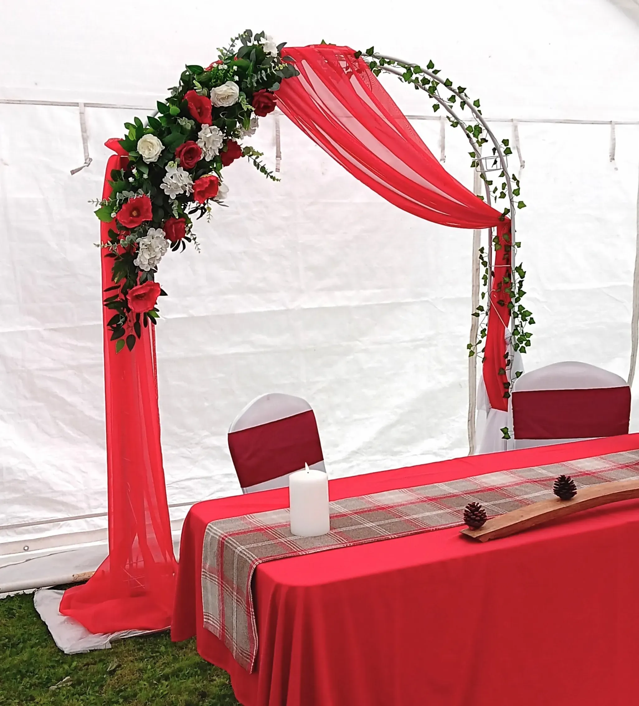 wedding arch decorated in red florals and fabric