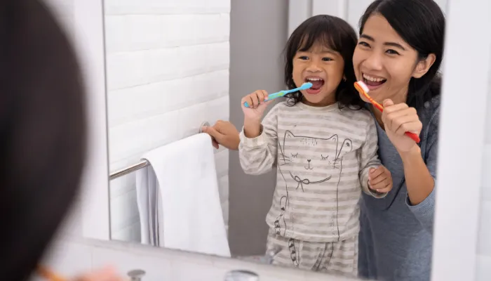 Mom and daughter brushing teeth and getting ready for school.