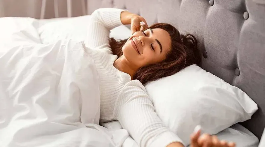 Close-up image of a resting person, with a focus on closed eyes, smiling face.