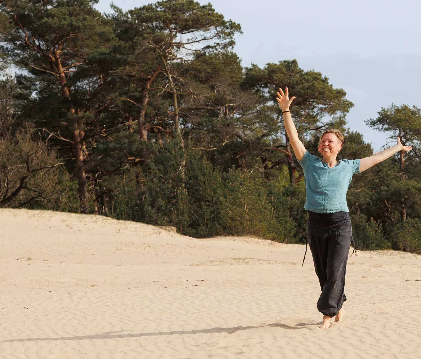 Ingrid met open armen en lachend in het zand