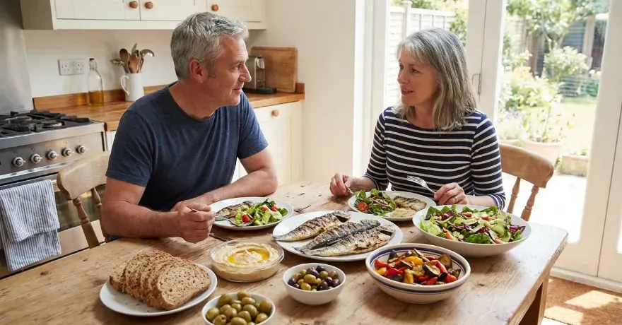 A middle-aged couple at their kitchen table eating a Mediterranean-style balanced diet.