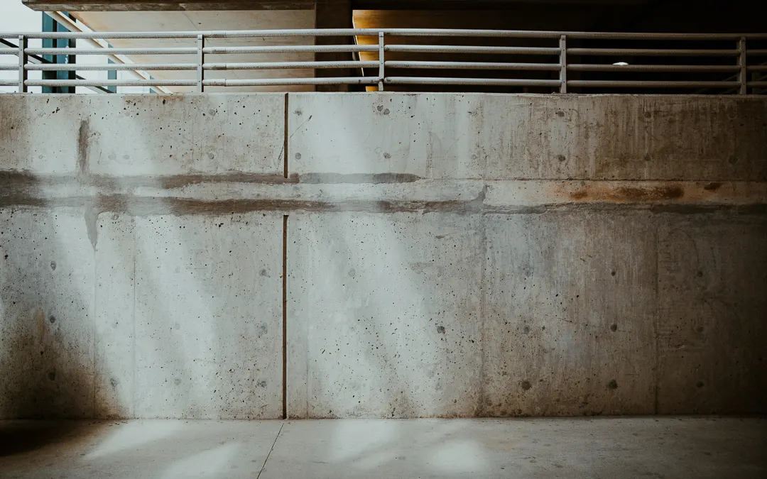 image of completely concrete industrial building with doorless entryway in center, 4ft wal n left hand side of image, and railing on right