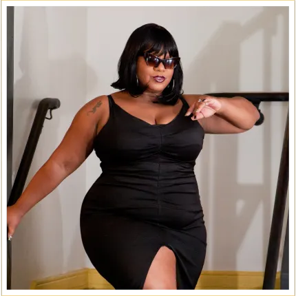 Curvy woman wearing shades and a sexy black dress walking down stairs